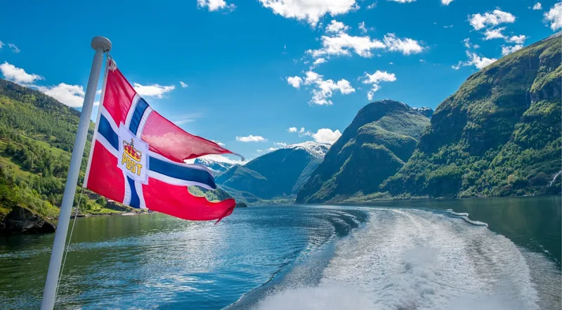 The Norwegian flag flying from the stern of a fjord cruise boat